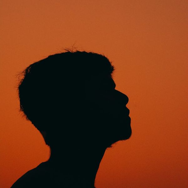 Silhouette of a person meditating against a calm, dark background.
